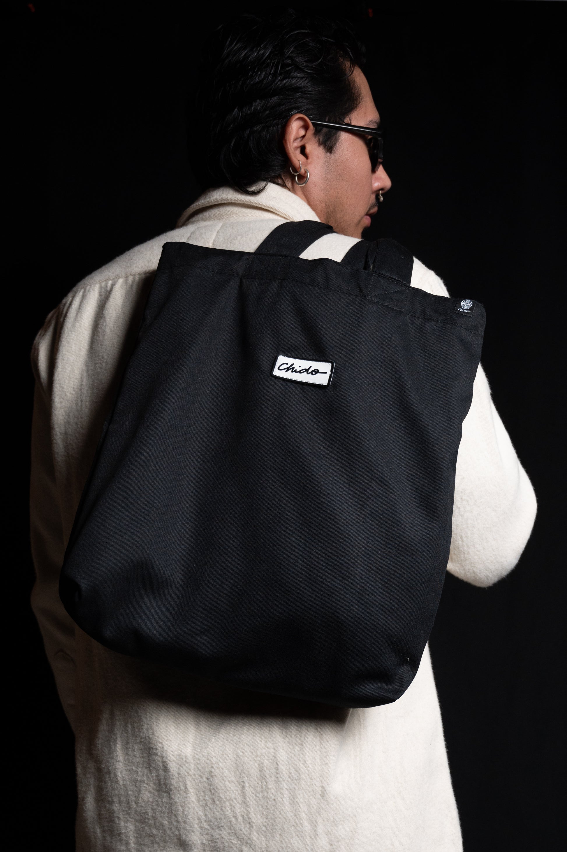 Persona usando tote bag negra CHIDO estilo streetwear