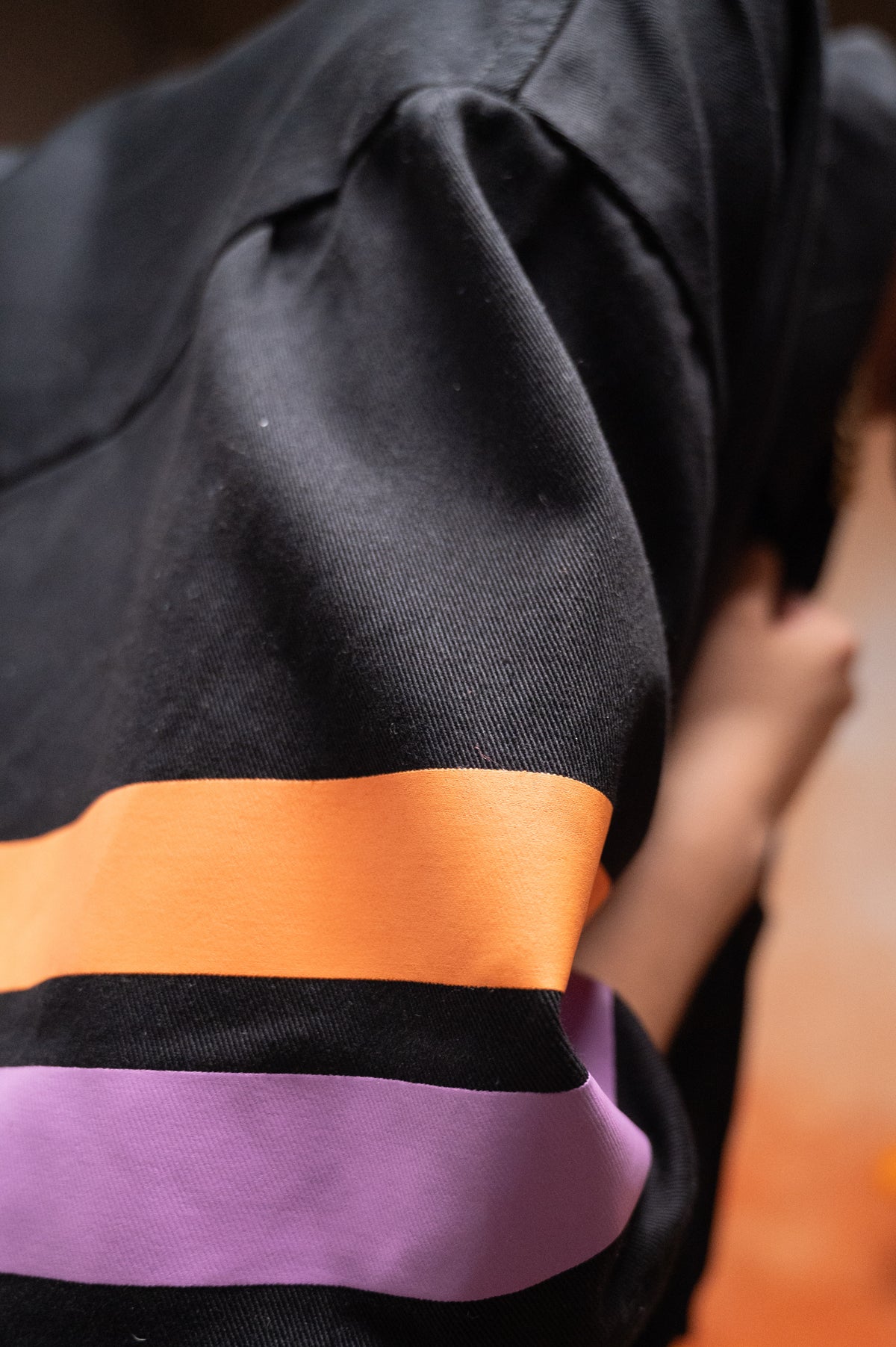 Detalle de la manga con franjas inspiradas en el Día de Muertos de la Sobrecamisa Boxy Fit Negra EEE.
