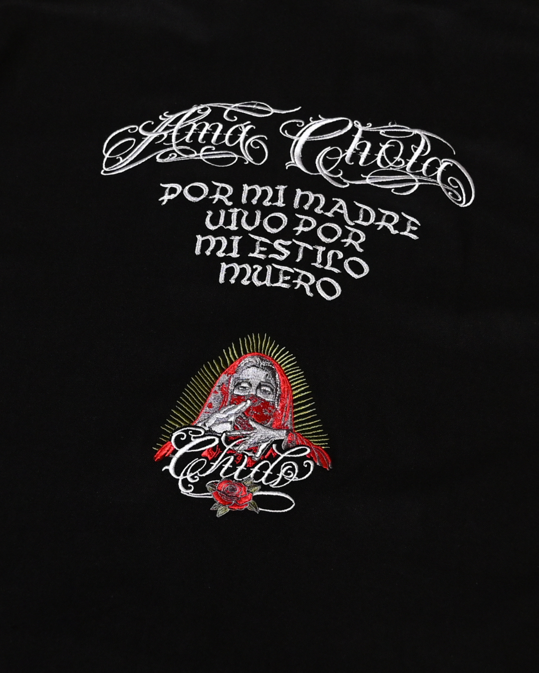 Detalle del bordado Amá Chola en la espalda de una camisa boxy negra CHIDO.