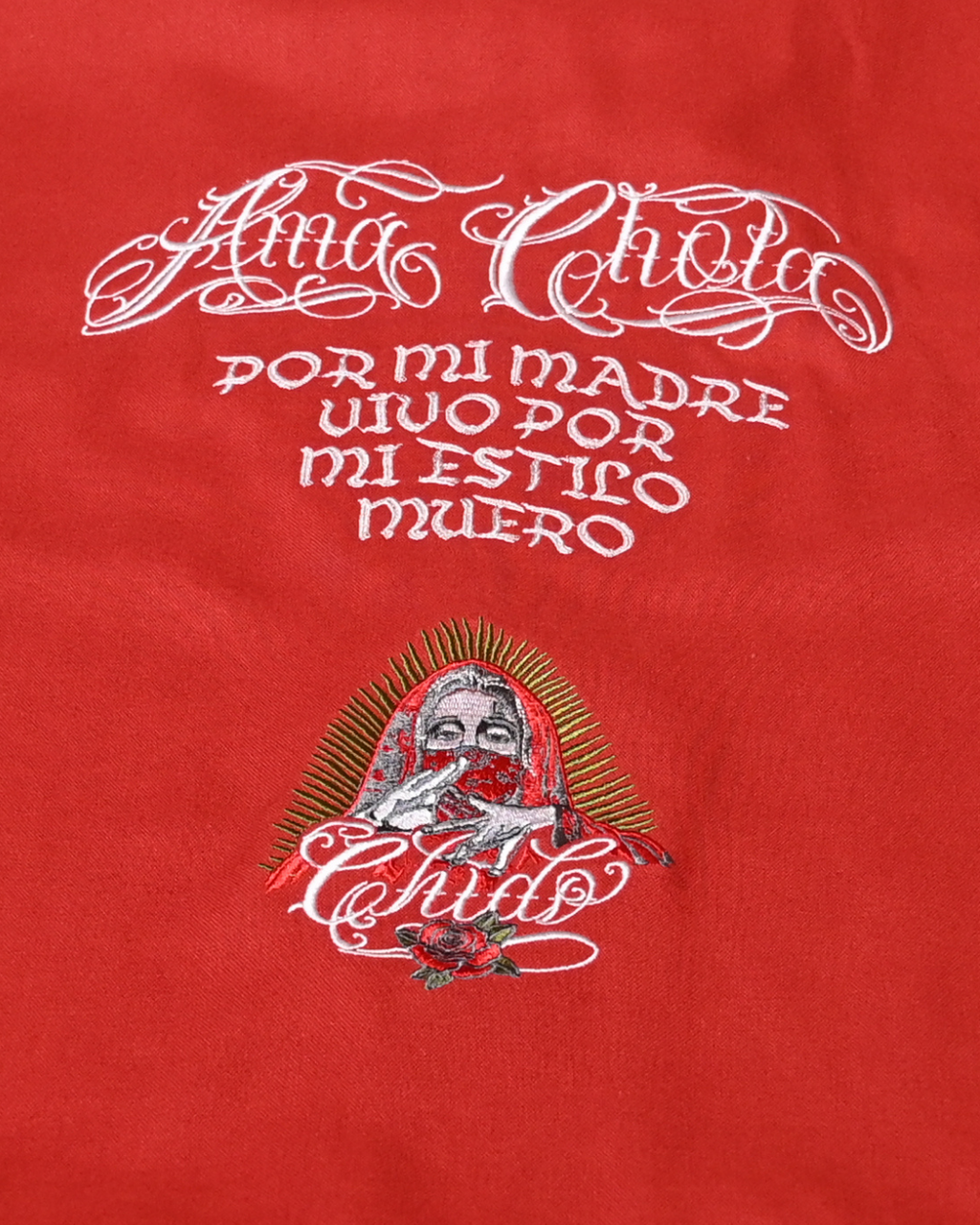 Detalle del bordado Amá Chola en la espalda de una camisa boxy roja CHIDO.