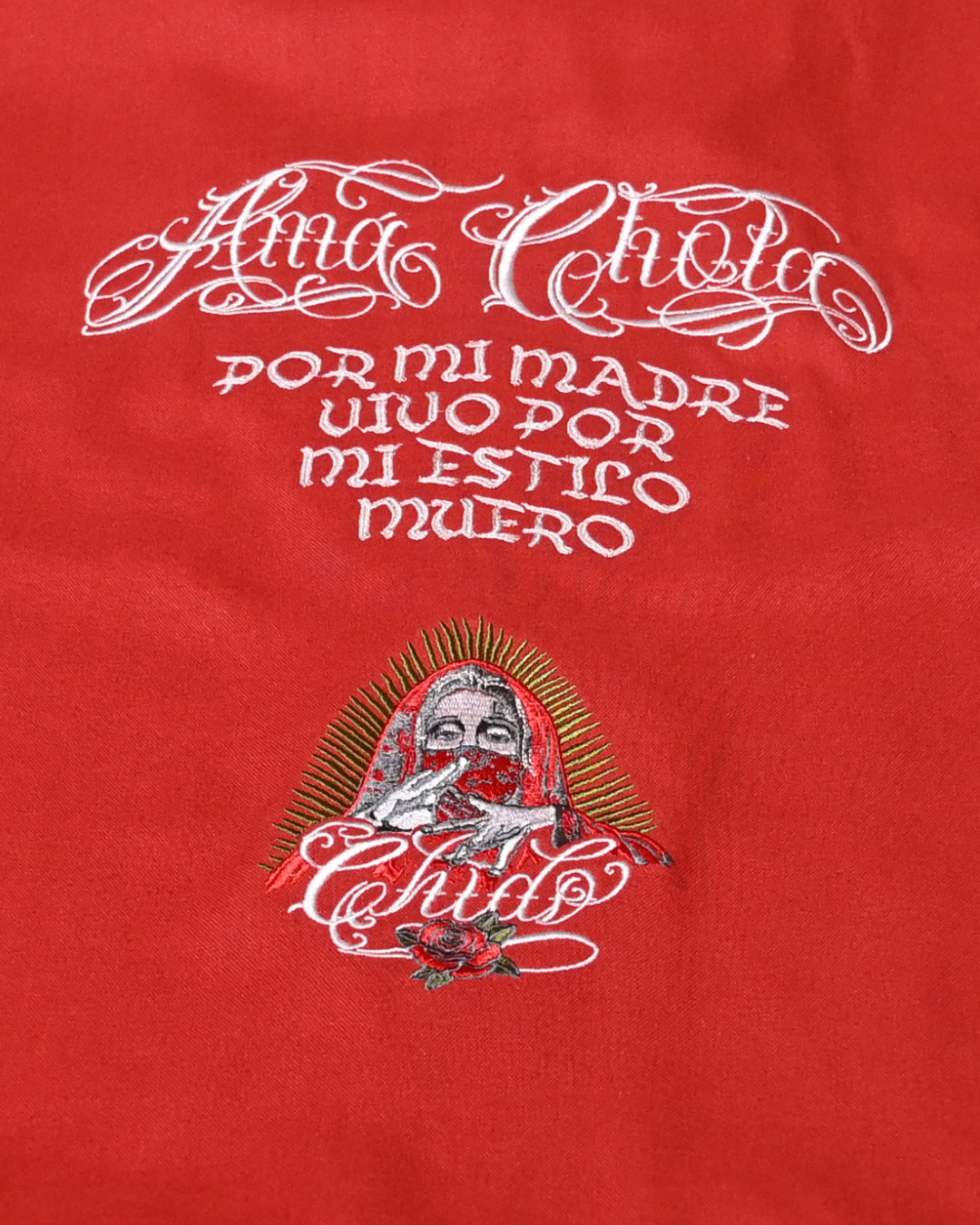 Detalle del bordado Amá Chola en la espalda de una camisa boxy roja CHIDO.