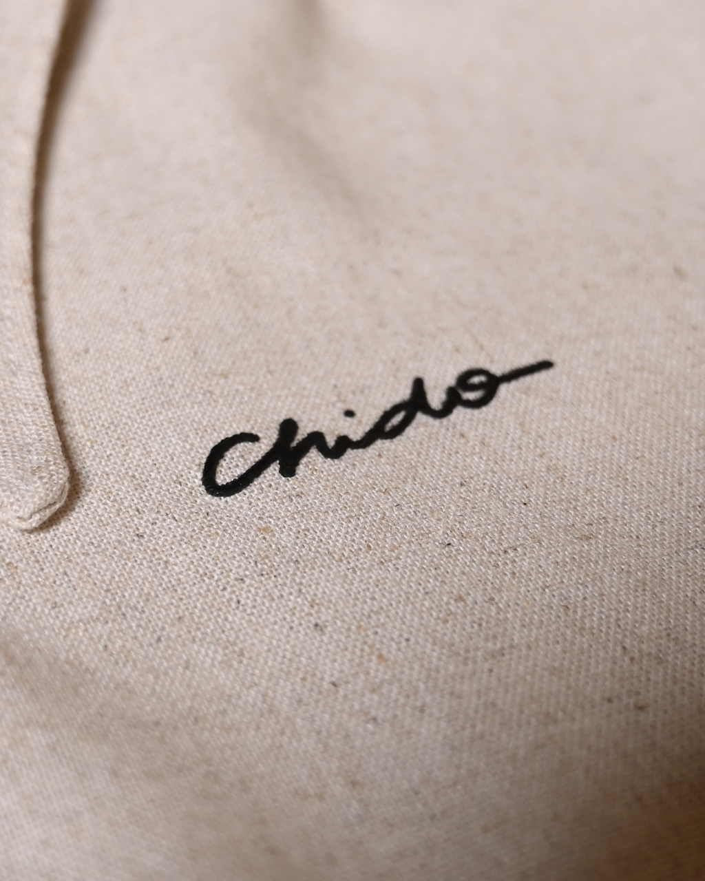 Detalle del bordado CHIDO en camisa de lino beige