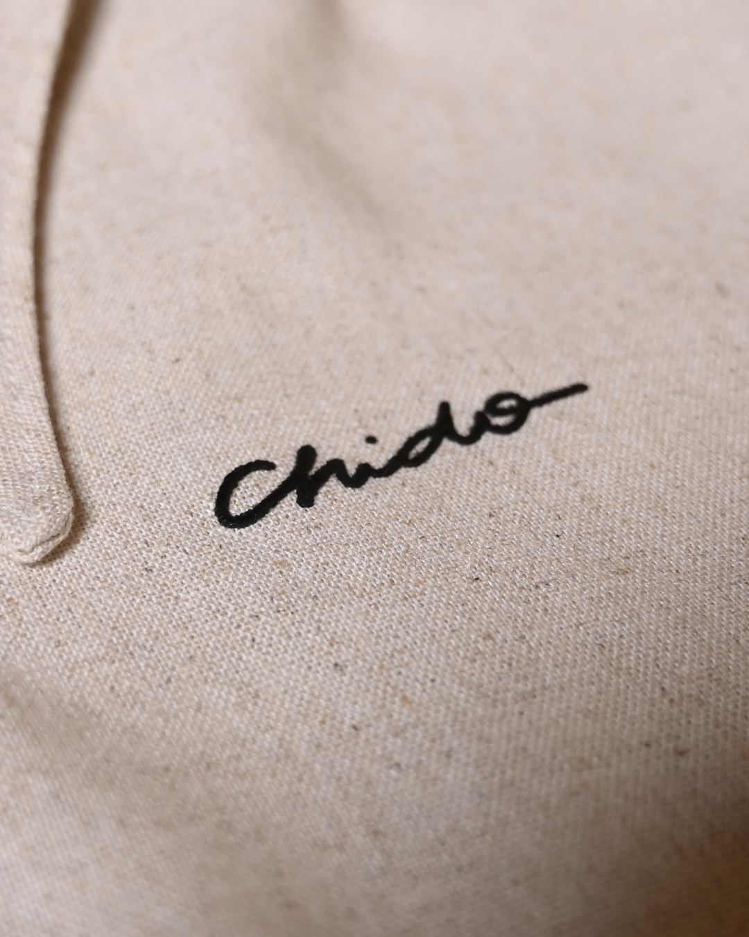 Detalle del bordado CHIDO en camisa de lino beige