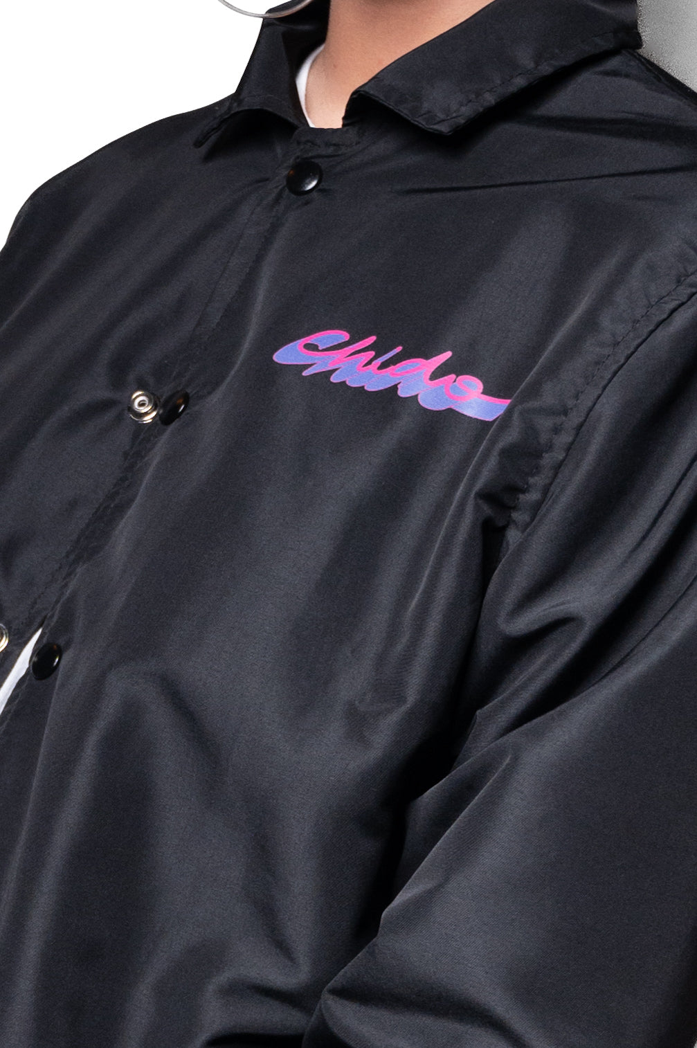 Logo bordado CHIDO sobre coach jacket negra
