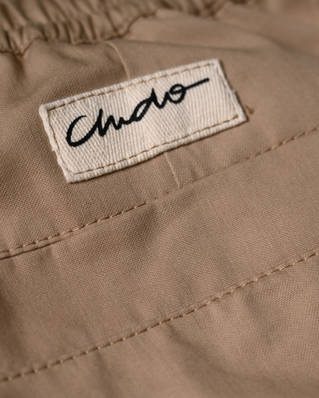 Detalle de etiqueta CHIDO en pantalón cargo beige
