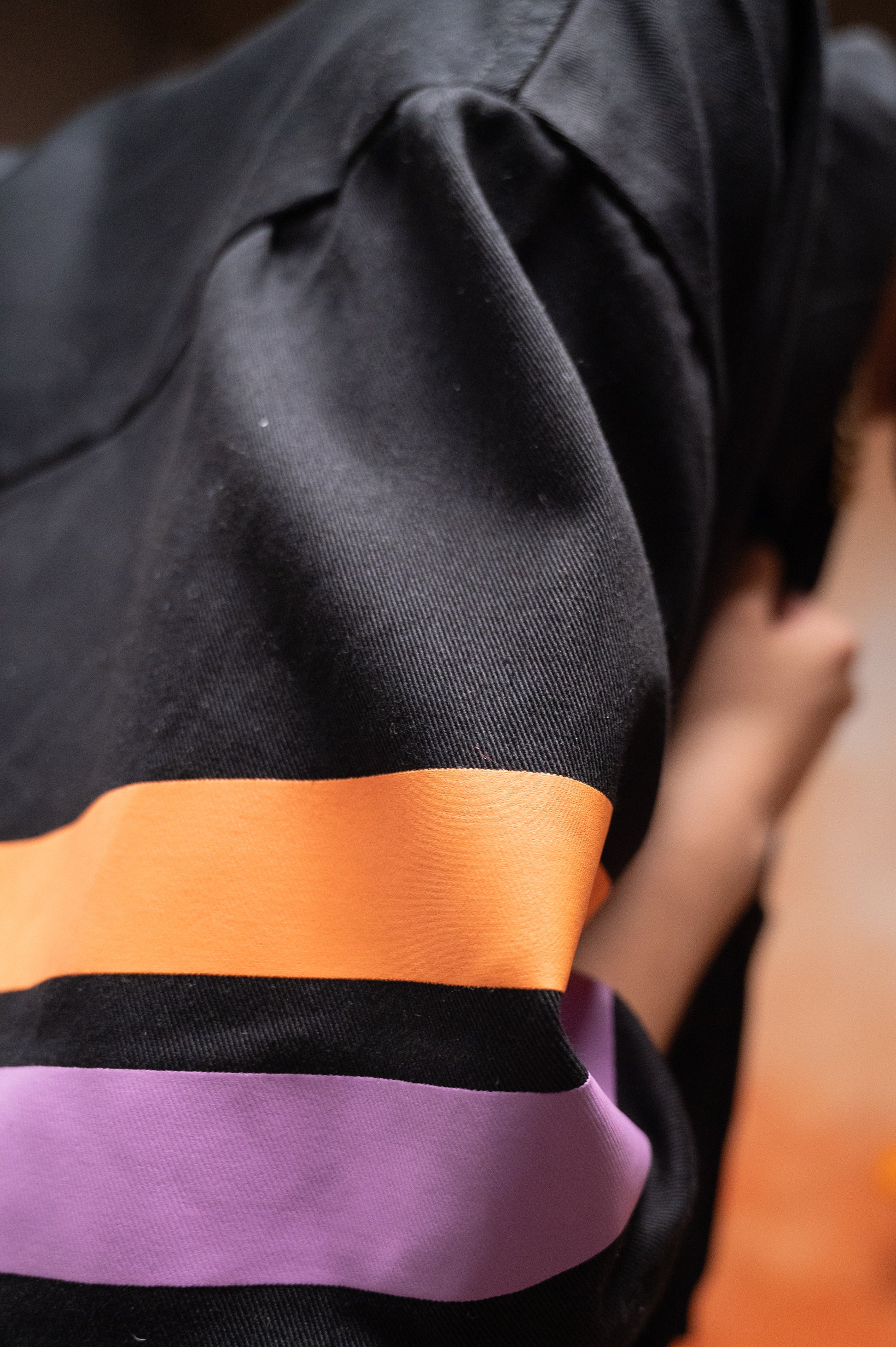 Detalle de la manga con franjas inspiradas en el Día de Muertos de la Sobrecamisa Boxy Fit Negra EEE.