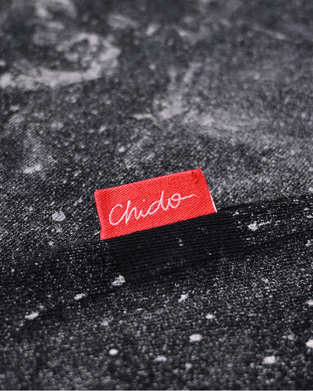 Detalle de etiqueta tejida CHIDO en playera tie dye oversize