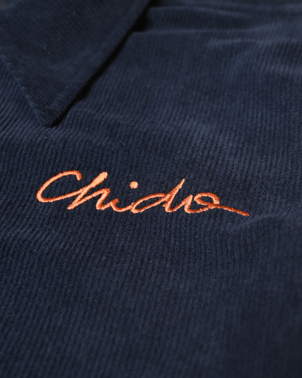 Embroidered CHIDO logo detail on navy corduroy jacket